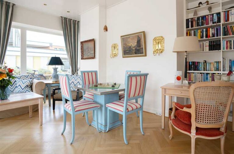 Heller Empfangsraum mit großen Fenstern mit Holzstühlen einem Tisch und einem Sofa